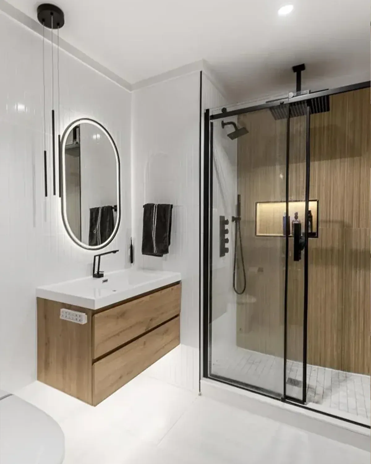Bathroom with walnut vanity, oval mirror and glass shower with wood-look tile
